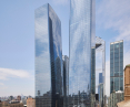 A cityscape with two tall reflective glass skyscrapers surrounded by smaller buildings and a clear sky.