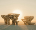 Wooden spiral structures under the setting sun in a desert landscape