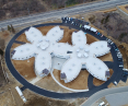 Aerial view of a building shaped like two flowers in a snowy landscape with a road in the background