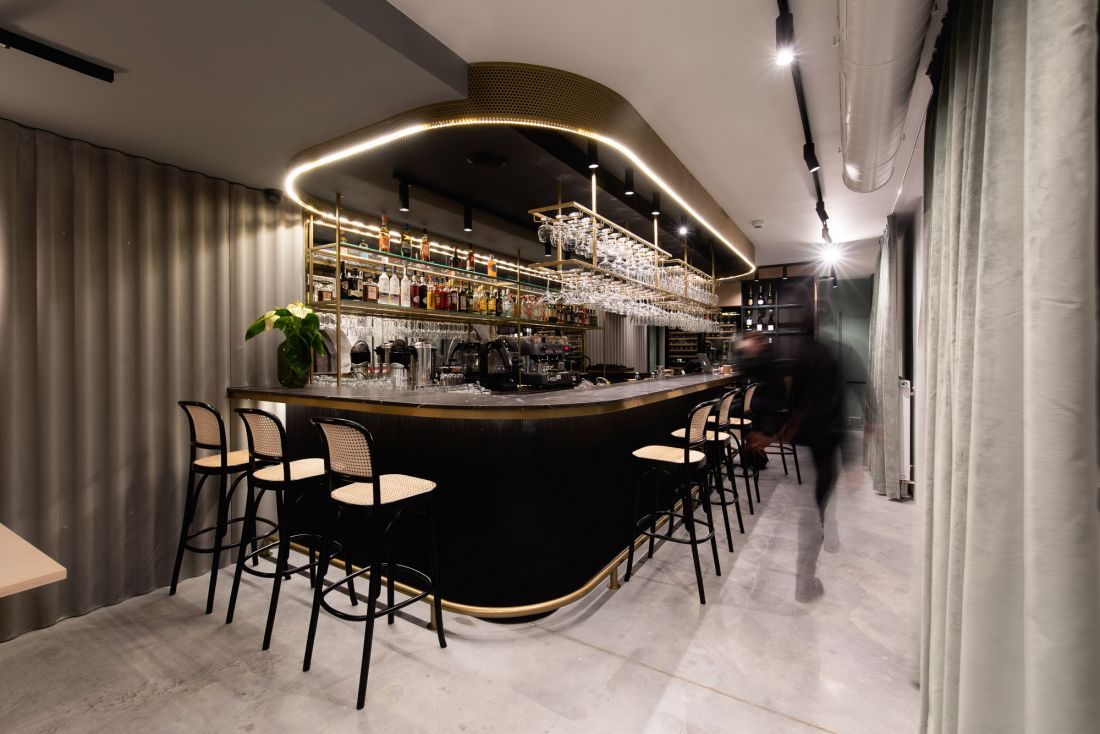 Czarno-złoty bar wyróżnia się na tle odcieni szarości dominujących w restauracji