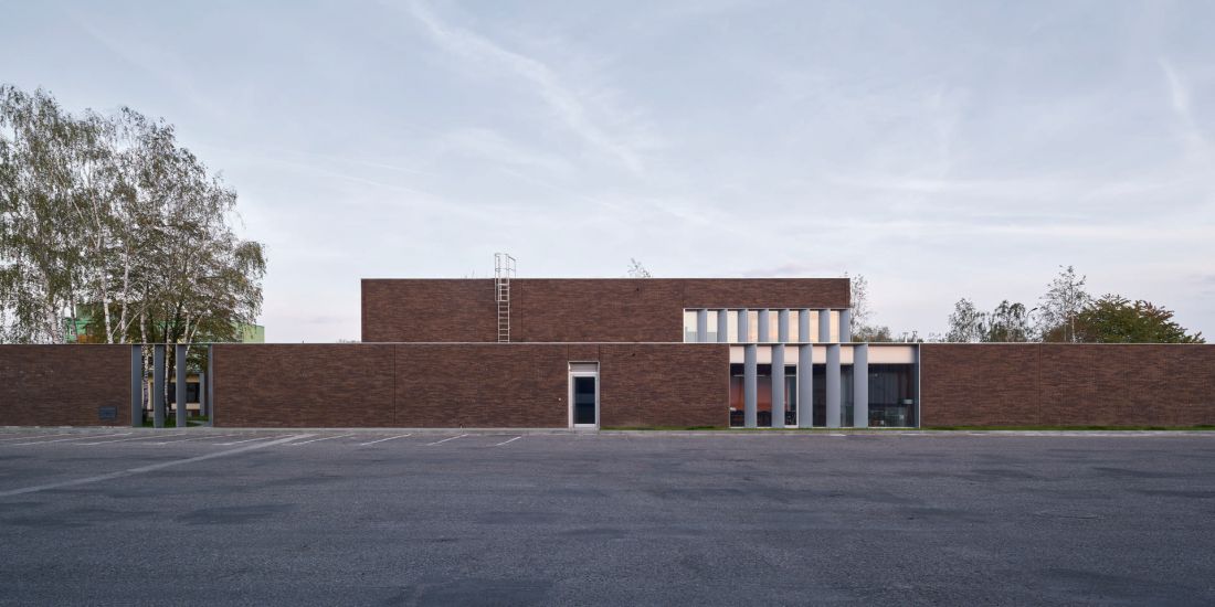 ceglany mur oddziela biurowiec od strefy przemysłowej
