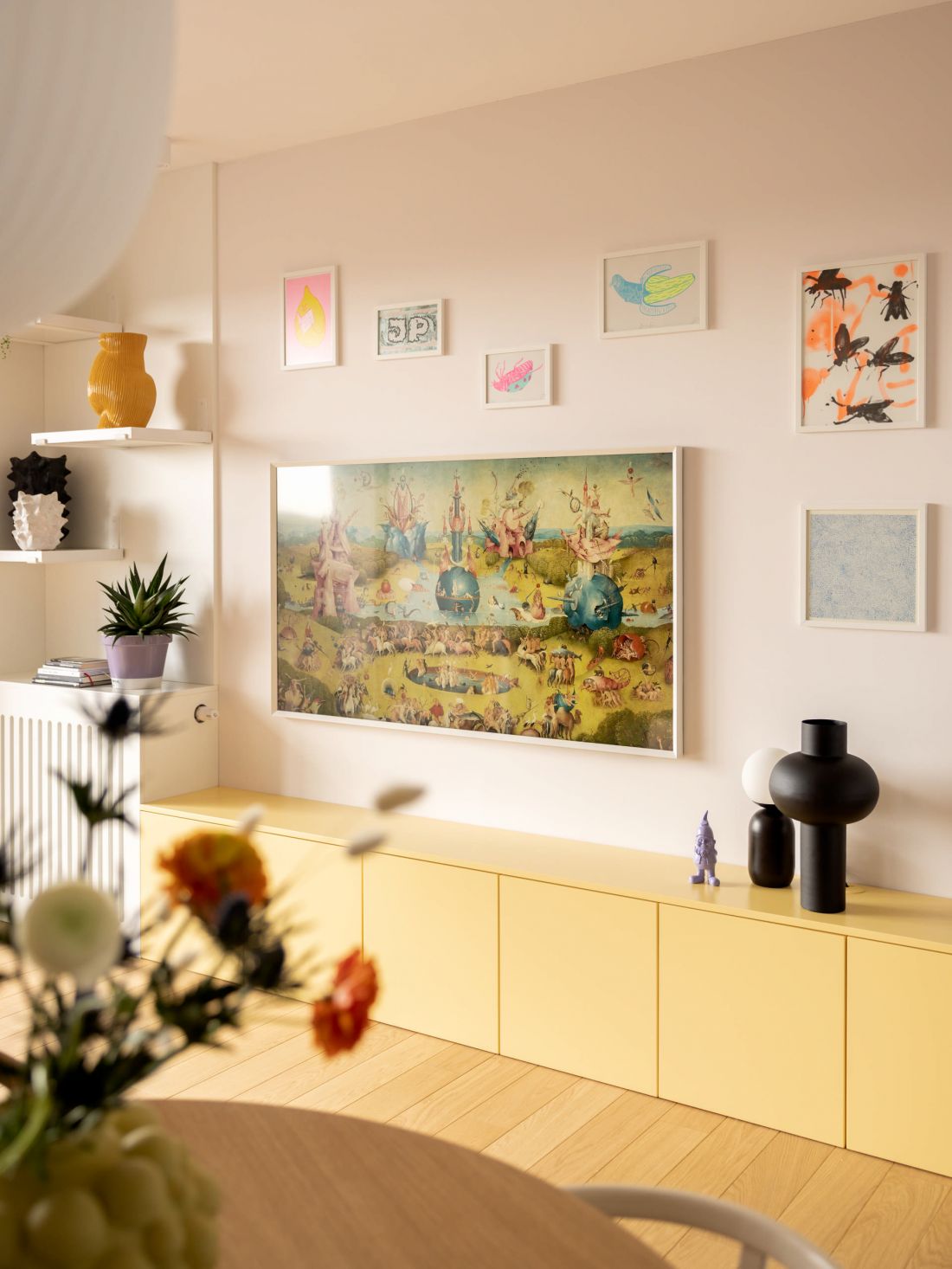 nad żółtą szafką stworzono domową galerię grafik i plakatów
