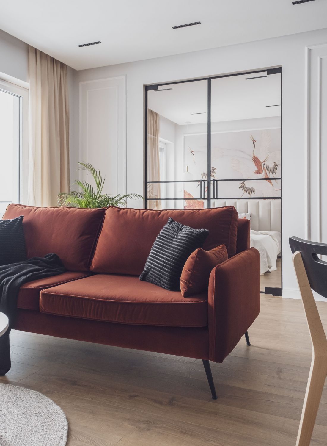 Ceglasta sofa ożywia stonowaną przestrzeń