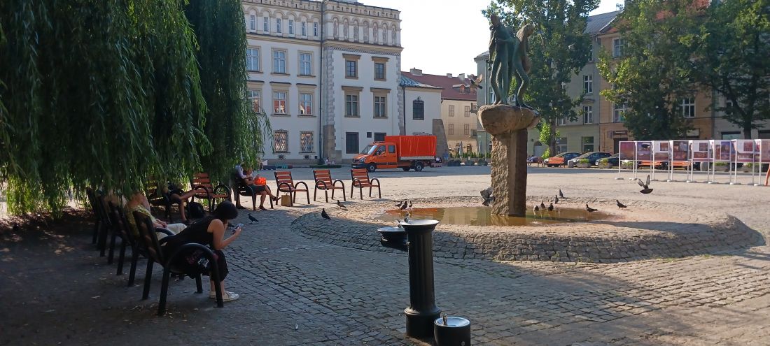 obok fontanny i drzew dostawiono ławki i krzesła miejskie