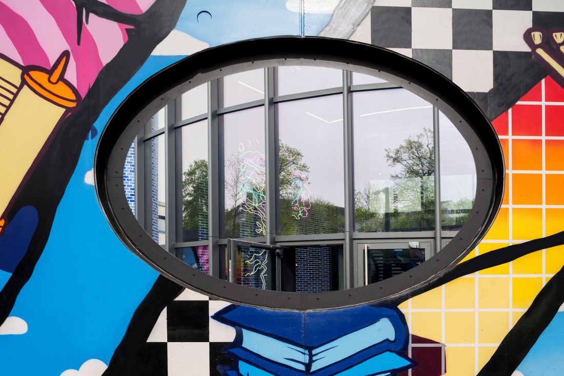 Dziura w murze z graffiti, przez którą można zajrzeć do Pears Judischer Campus