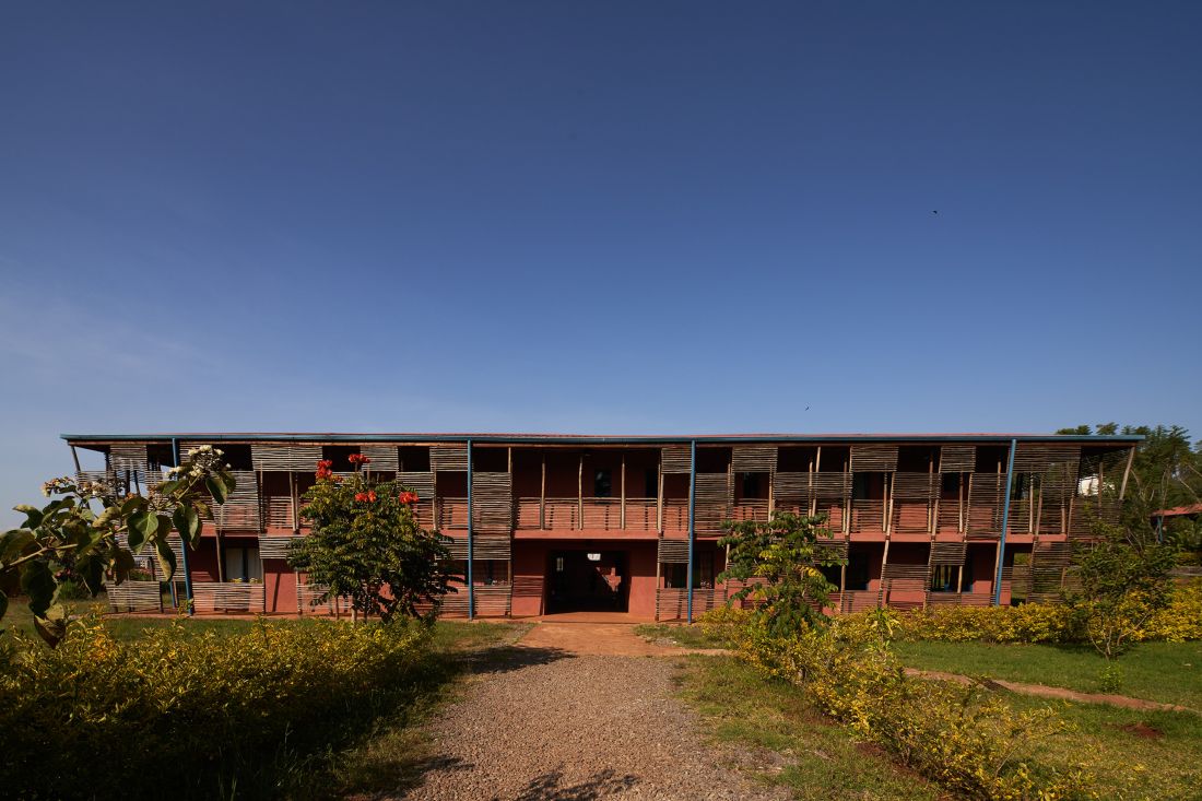 Dwupiętrowy budynek Busajo Campus od frontu, przylegający do ogrodu, w tle bezchmurne niebo