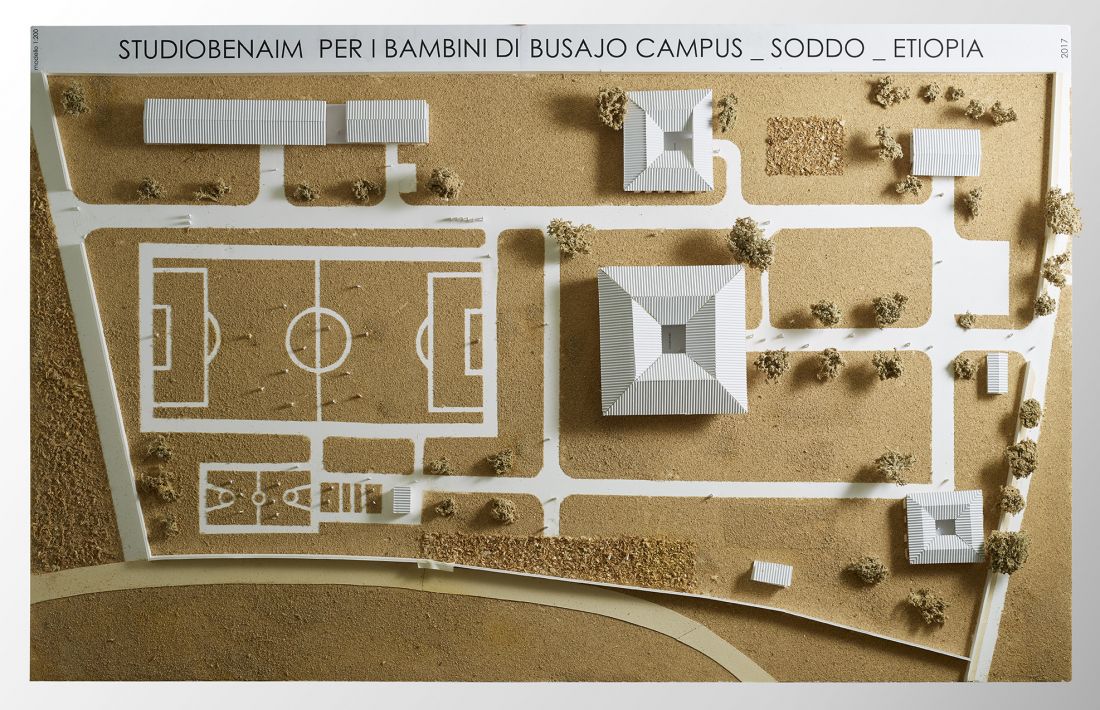 Model architektoniczny kampusu z budynkami o piramidowych dachach i boiskiem do piłki nożnej