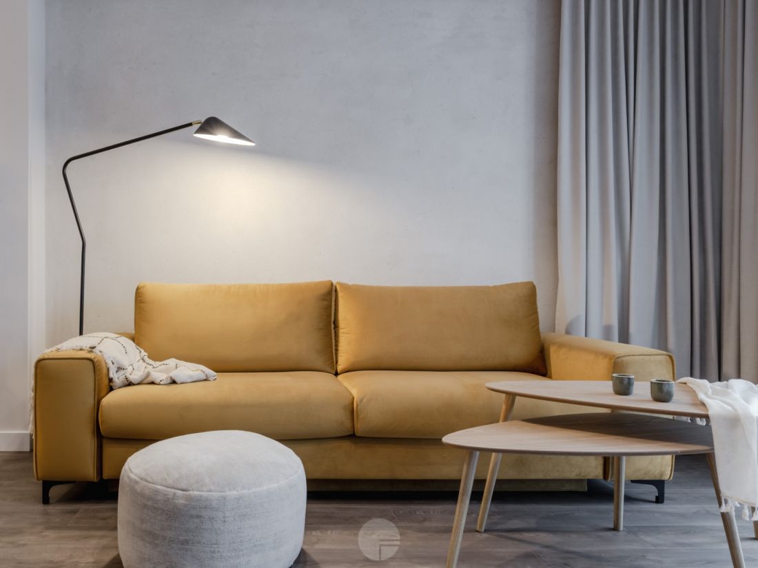 Musztardowa sofa stanowi barwny akcent w salonie