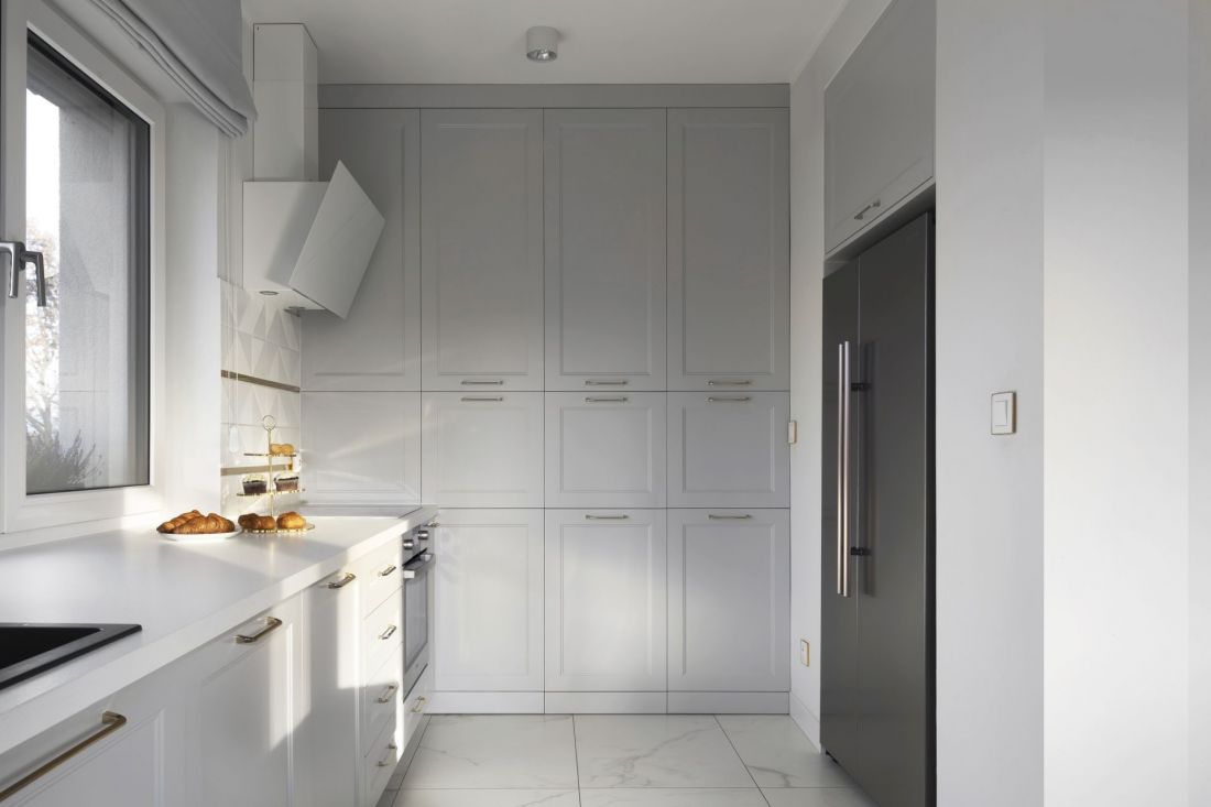 Nowoczesna kuchnia z eleganckimi frontami, złotymi wstawkami i płytką 3D - połączenie stylu, ergonomii i praktycznego designu.