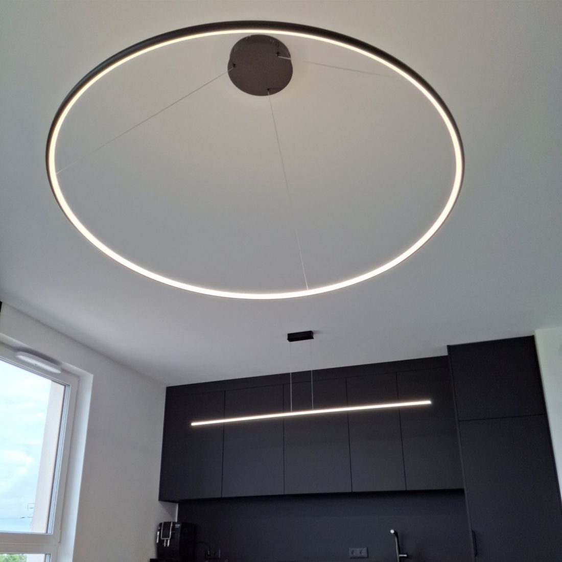  Lampa LED Orbit No.1 o dużej średnicy – nowoczesne oświetlenie kuchni z czarną zabudową i jadalnią, od LEDesign