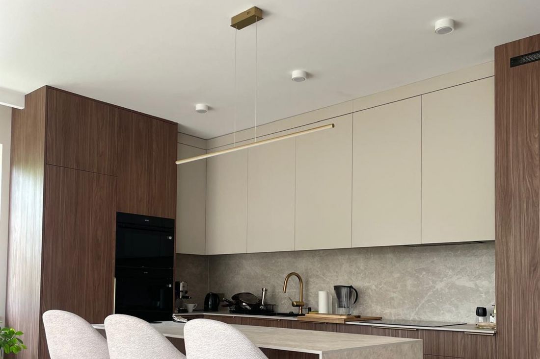 Nowoczesna lampa liniowa LED Led Line w kolorze złotym nad wyspą kuchenną w eleganckim wnętrzu