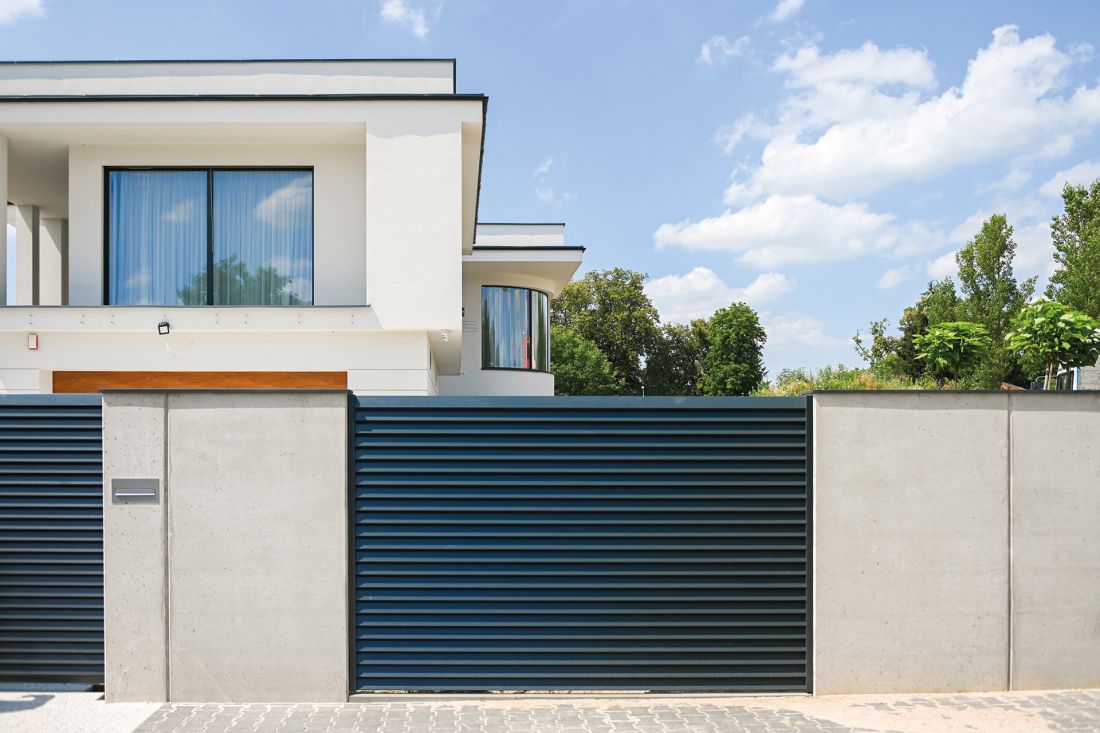 Ogrodzenie frontowe, wykonane z betonu architektonicznego z przęsłami typu żaluzja - z ocynkowanej stali, malowanej proszkowo