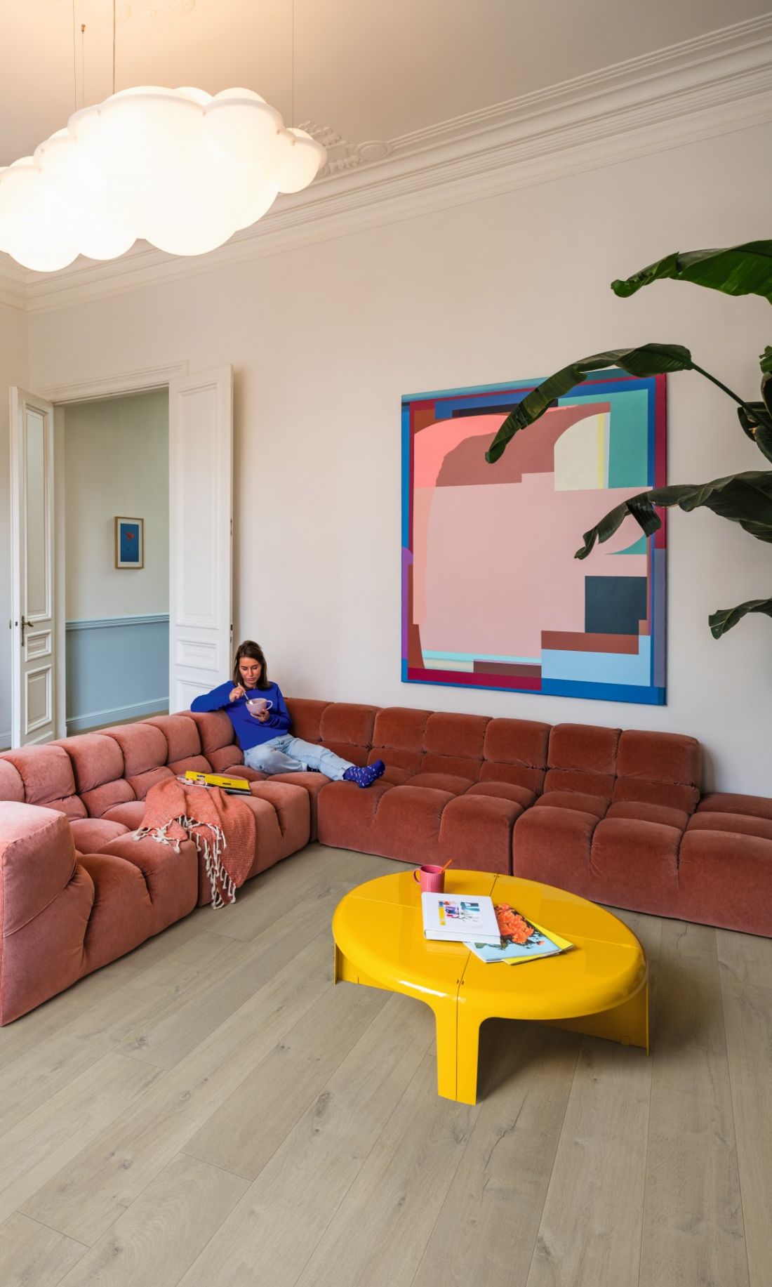 Miękka, pikowana sofa, jasna podłoga i graficzne dodatki pokazują, jak faktury budują we wnętrzu klimat retro bez dosłownej stylizacji