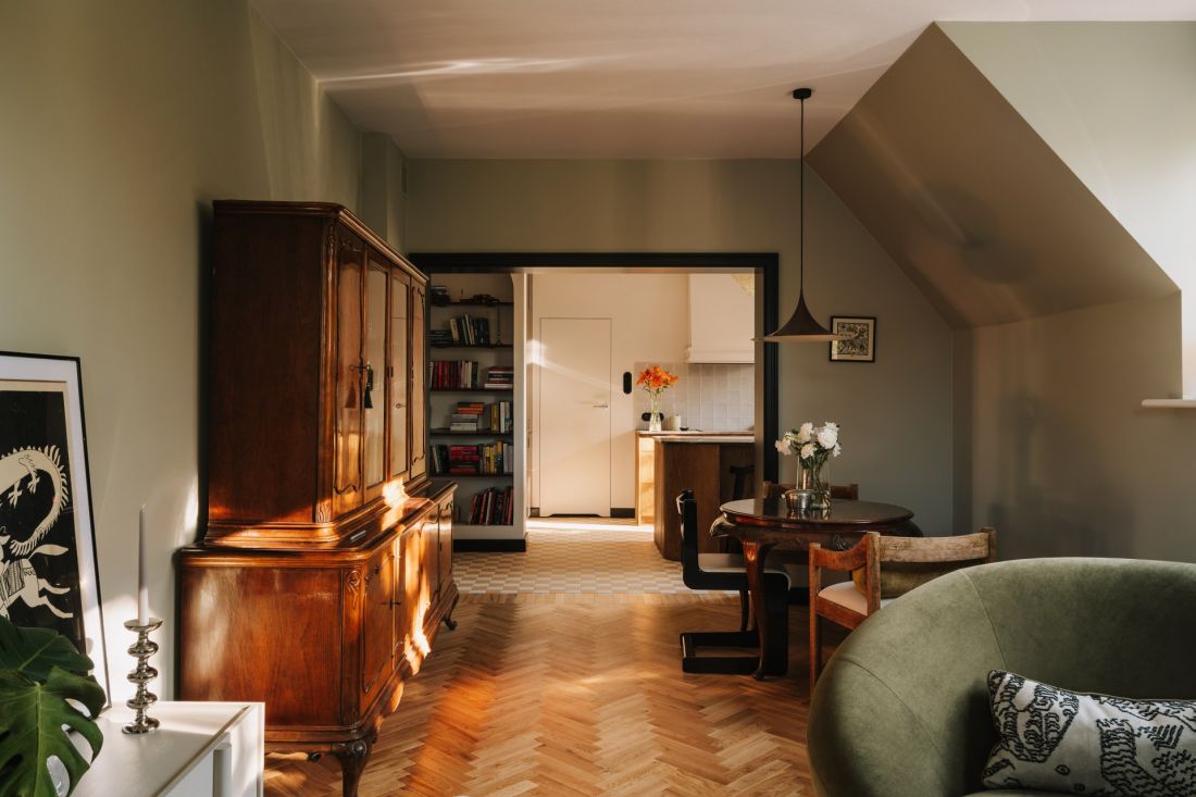 W salonie rodzinne meble i znaleziska vintage spotykają się z oliwkową zielenią i drewnianą podłogą ułożoną w jodełkę