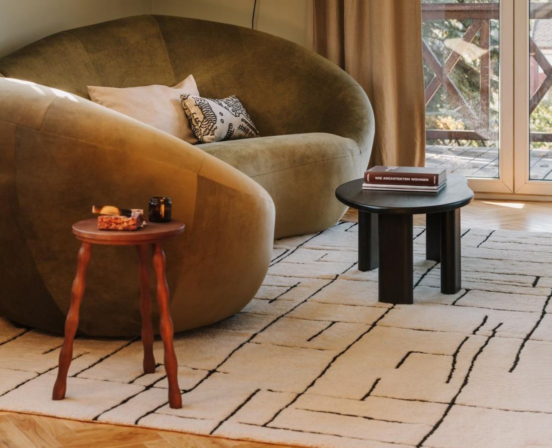 Oliwkowa sofa o miękkiej, obłej formie przełamuje geometryczne skosy salonu