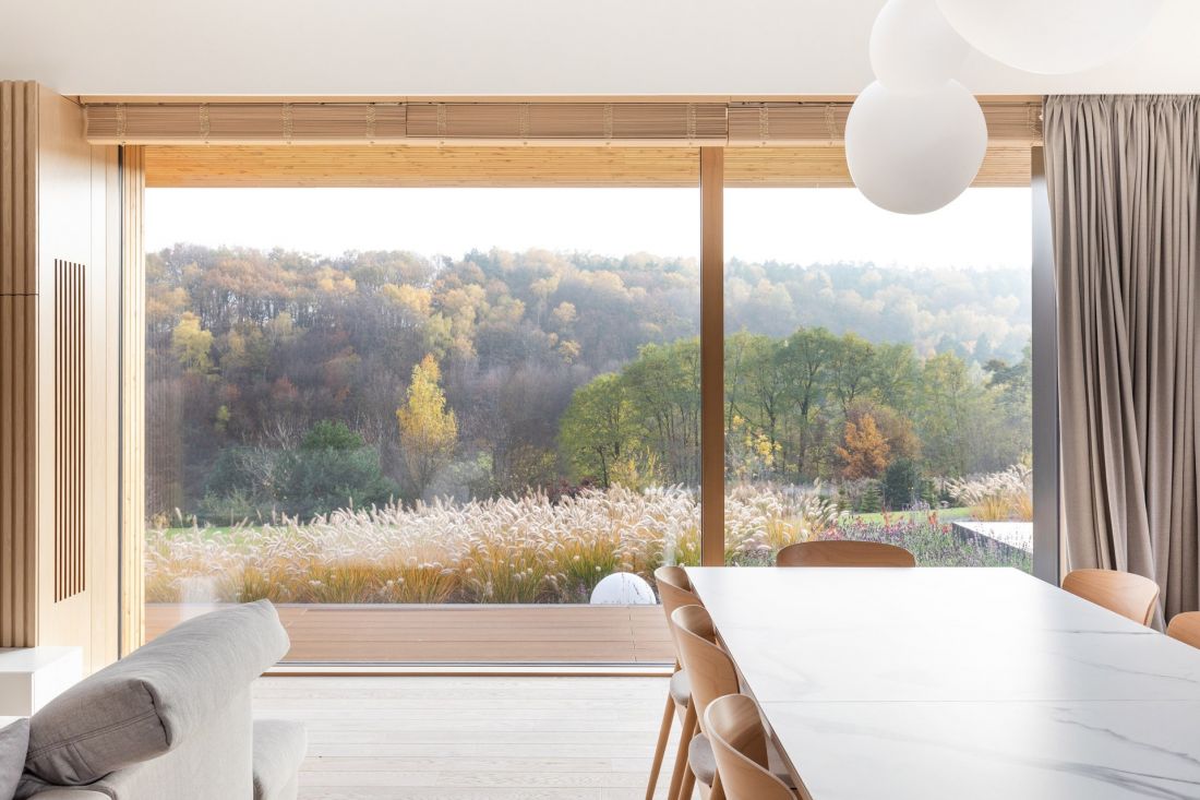 Panoramiczne przeszklenie w jadalni Forrest View House kadruje widok na Las Michałowicki, który zmienia się wraz z porami roku