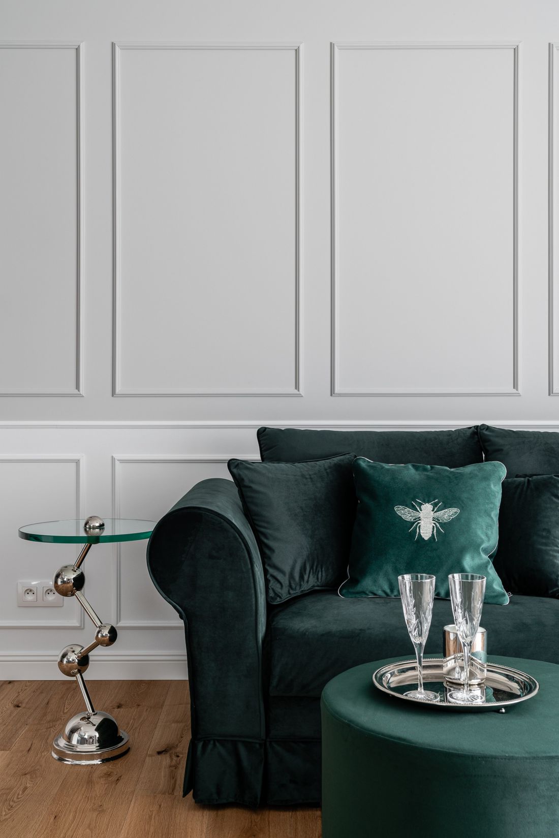 Sofa w kolorze butelkowej zieleni w towarzystwie ozdobnych stolików