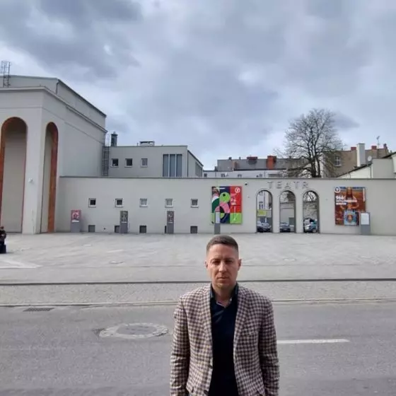 Radny Tomasz Dzionek na tle niemal bezdrzewnego placu przed Teatrem Fredry w Gnieźnie