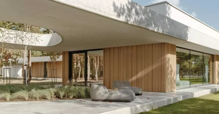 Elewacja domu betOnowego to harmonijne połączenie surowego betonu i jasnej drewnianej okładziny ściennej z pionowymi podziałami