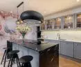 Połączenie kamienia naturalnego Cosmic Black na wyspie kuchennej, ze spiekiem kwarcowym Neolith, Abu Dhabi na blatach oraz okładzinie ścienne