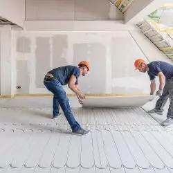 Montaż dodatkowej płyty gipsowo-włóknowej fermacell® o gr. 10 mm, która jest przyklejana i przykręcana jako przykrycie instalacji ogrzewania podłogowego fermacell® Therm 25