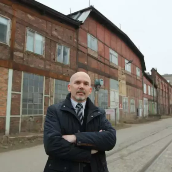 Dariusz Chmielewski na tle zespołu Stoczni Cesarskiej w Gdańsku, którą w poprzedniej kadencji wpisał do rejestru zabytków