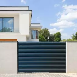 Ogrodzenie frontowe, wykonane z betonu architektonicznego z przęsłami typu żaluzja – z ocynkowanej stali, malowanej proszkowo