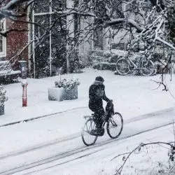 mężczyzna jadący na rowerze po zaśnieżonej ulicy