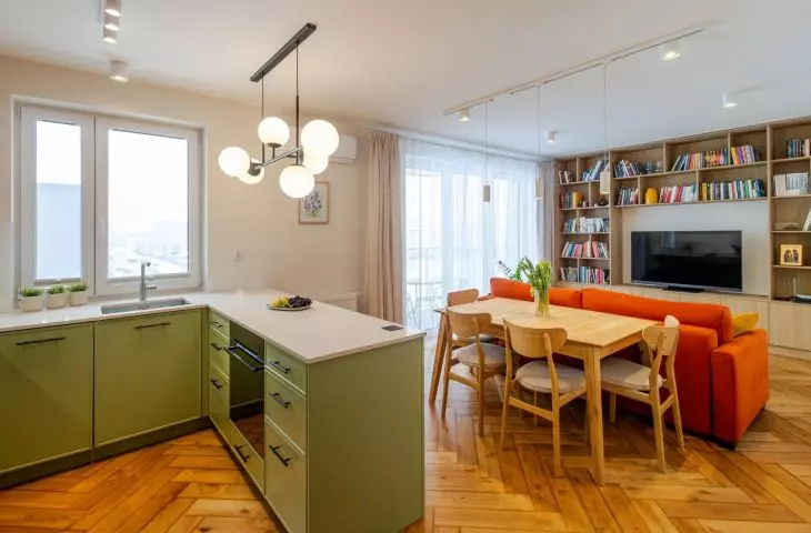 Zielona kuchnia i pomarańczowa sofa. 77-metrowe mieszkanie w Krakowie projektu ML STUDIO