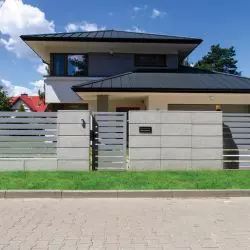 Ogrodzenie frontowe wykonane z betonowych bloczków architektonicznych. Dopełnienie stanowią przęsła palisadowe