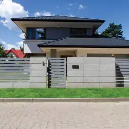 Ogrodzenie frontowe wykonane z betonowych bloczków architektonicznych. Dopełnienie stanowią przęsła palisadowe