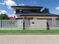Ogrodzenie frontowe wykonane z betonowych bloczków architektonicznych. Dopełnienie stanowią przęsła palisadowe