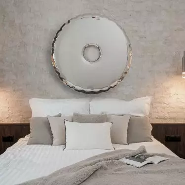 In a central place above the bed is a mirror Rondo by Oskar Zięta