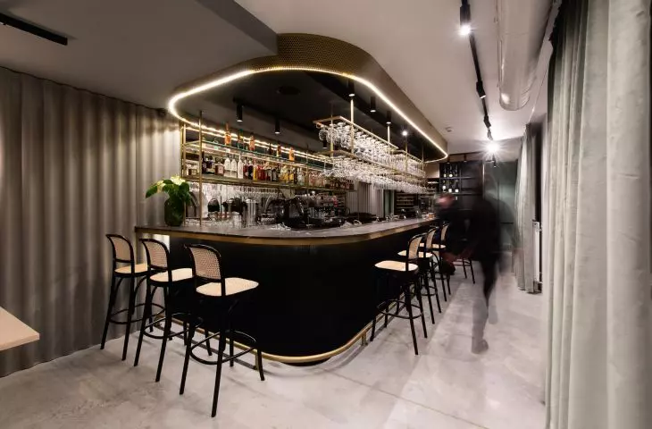 Czarno-złoty bar wyróżnia się na tle odcieni szarości dominujących w restauracji