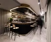 Czarno-złoty bar wyróżnia się na tle odcieni szarości dominujących w restauracji