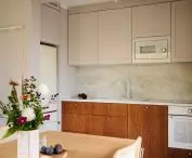 Fornirowane, frezowane fronty dolnych szafek kuchennych w karmelowym kolorze, architektka zestawiła z prostymi, beżowymi frontami szafek górnych
