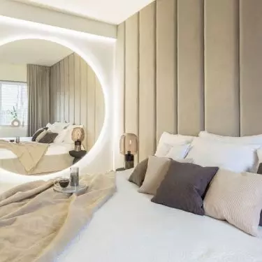 In the bedroom there is a large illuminated mirror