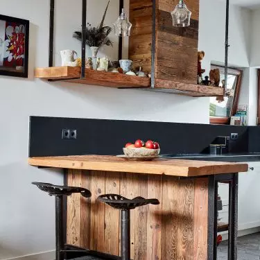 Kitchen furniture made of Light Brown Sun-Fired Planks, with countertop with preserved old hand-chipped surface, hood housing made of recycled metal profiles; Stool - hocker metal saddle from an old farm machine