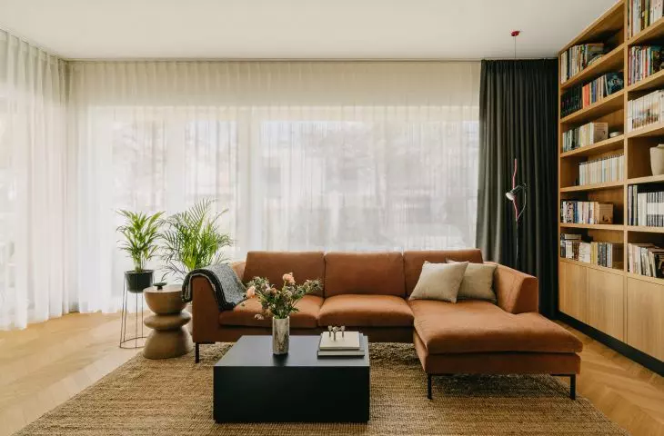 corduroy sofa, beige carpet and soft curtains add coziness to the interior