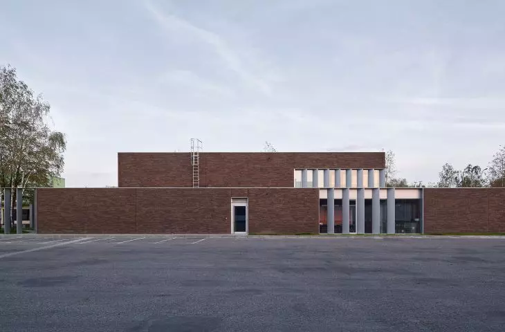 ceglany mur oddziela biurowiec od strefy przemysłowej