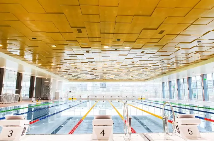 A gold metal ceiling made of Knauf Ceiling Solutions panels adorns a swimming pool in Uster, Switzerland