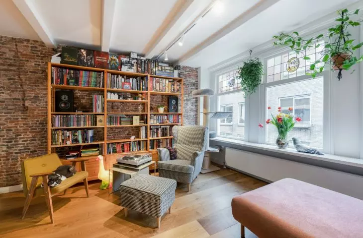 An important element of the living room is an old brick wall with a bookcase