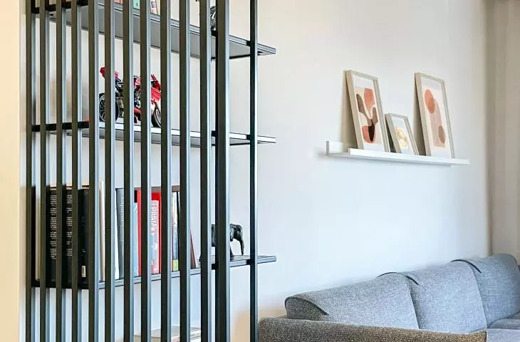 A steel shelving unit separates the entrance area from the living area