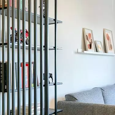 A steel shelving unit separates the entrance area from the living area