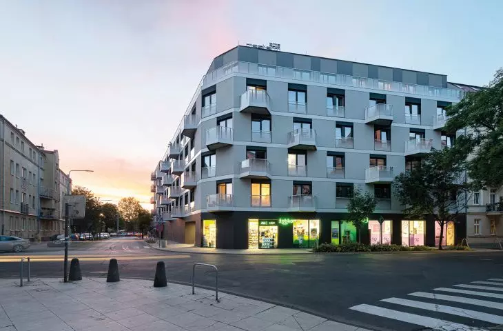 a residential building on Fabryczna Street in Poznań; the characteristic elements of the facade are the inter-storey strips made of aluminum, surrounding the balconies