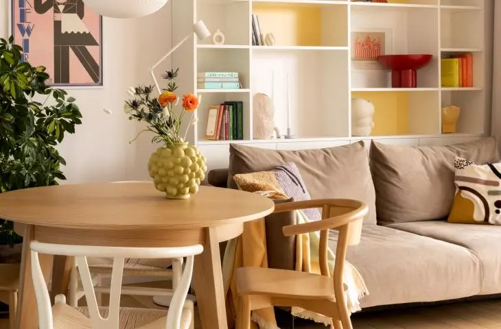 in the white and yellow bookcase next to books and colorful accessories there was a place for a cat bed