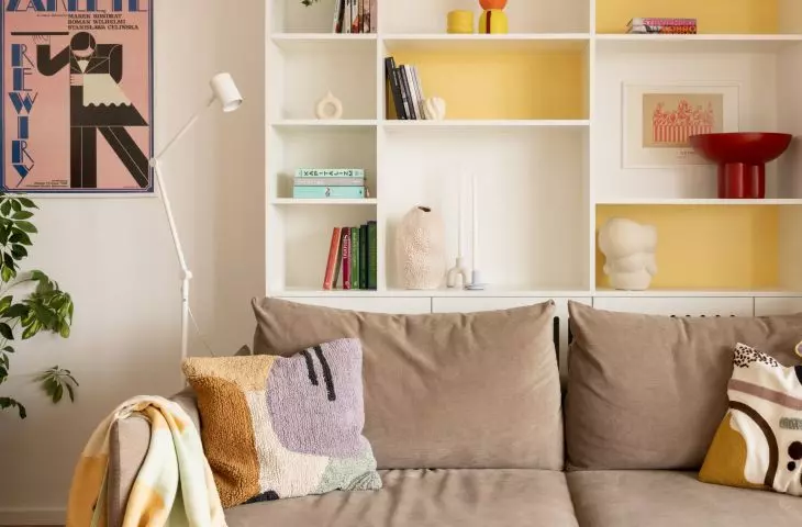 Colorful accents in the living area, red table, yellow bookcase and pink poster