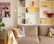 Colorful accents in the living area, red table, yellow bookcase and pink poster