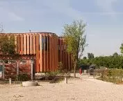 od strony ulicy wyłom zlokalizowano niewielki budynek z drewniano-szklaną elewacją 