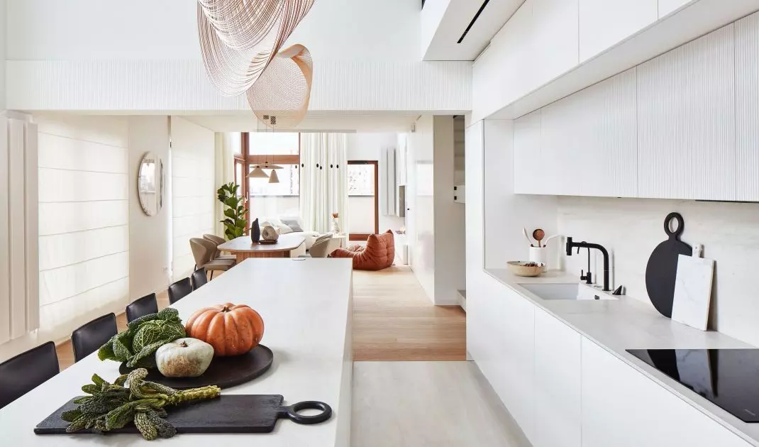 Above the long kitchen island hang sculptural lamps